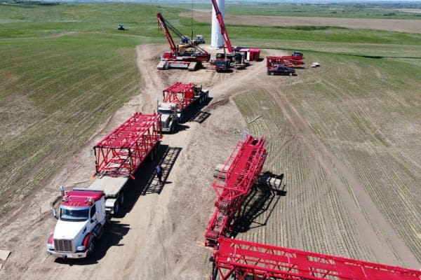 Tundra trucks lined up, ready to be offloaded, providing service and support for the construction of a large tower crane in wind turbine building.