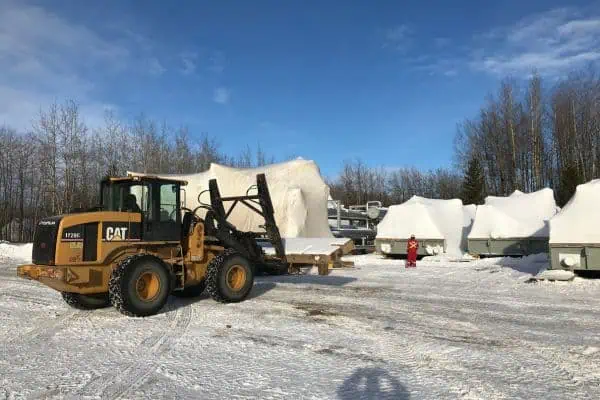 Tundra personnel positioning equipment in their secure storage yard utilizing a front end loader heavy equipment